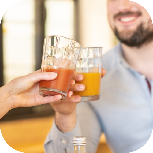 Verres de jus de pamplemousse rose de couleur orange et rose mains trinquent sourire -  Juste le Choix du Fruit