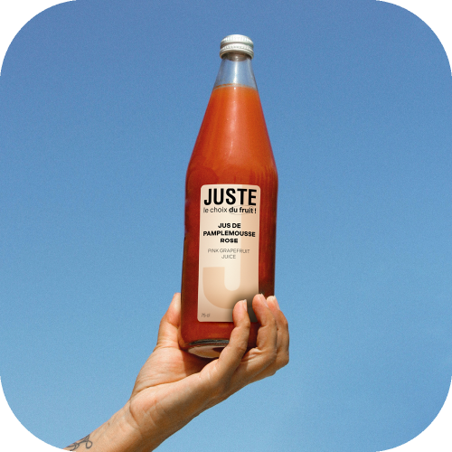 Bouteille en verre de jus de pamplemousse rose de couleur orange rose 75 cl de face main ciel -  Juste le Choix du Fruit