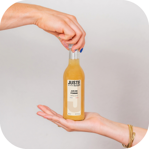 Bouteille en verre de jus de pomme de couleur jaune 25 cl de face mains -  Juste le Choix du Fruit
